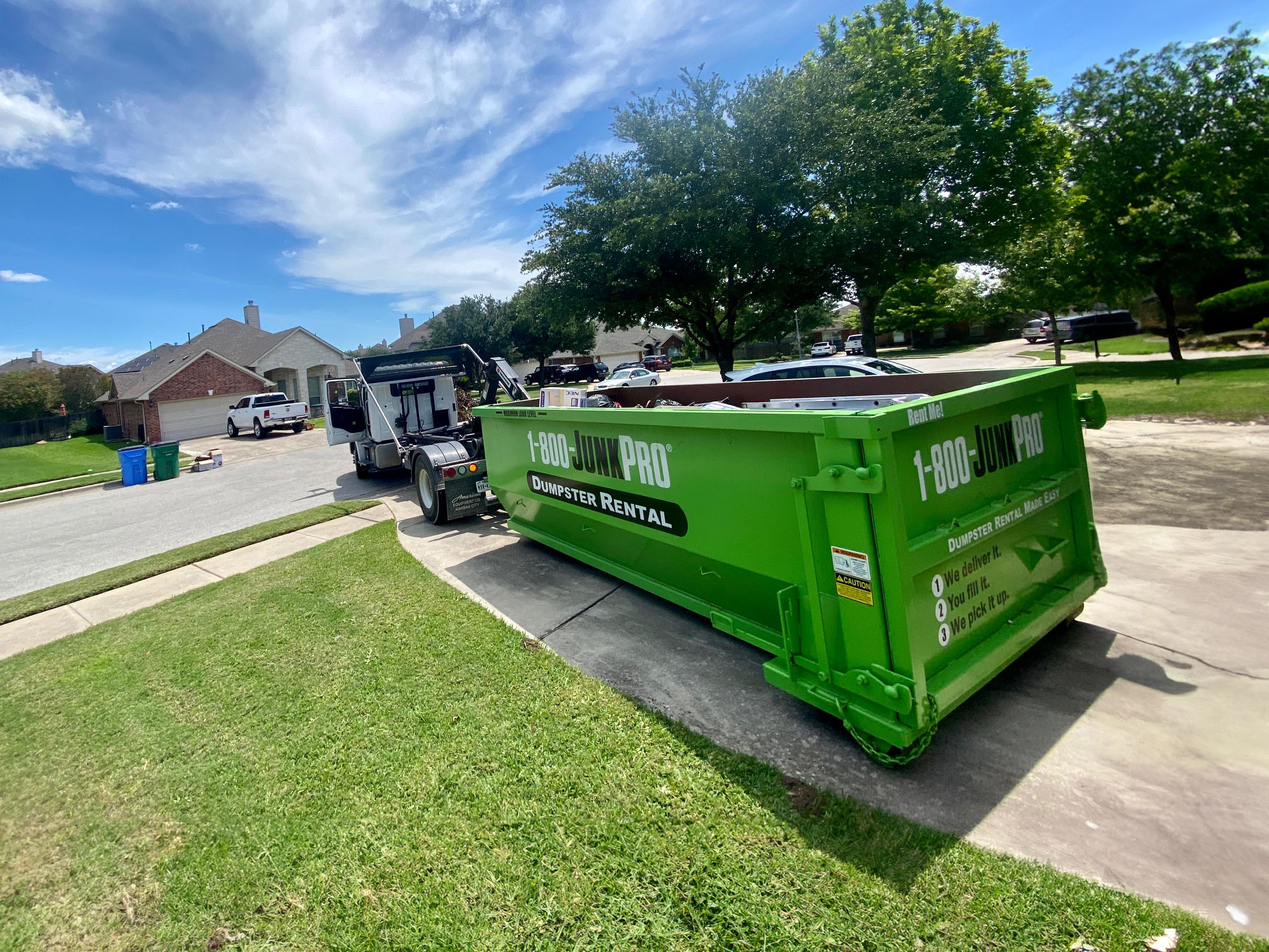 1-800-JunkPro Dumpster being uloaded on a home driveway