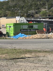 A Large Rented Dumpster in a commercial parking lot surrounded by debris