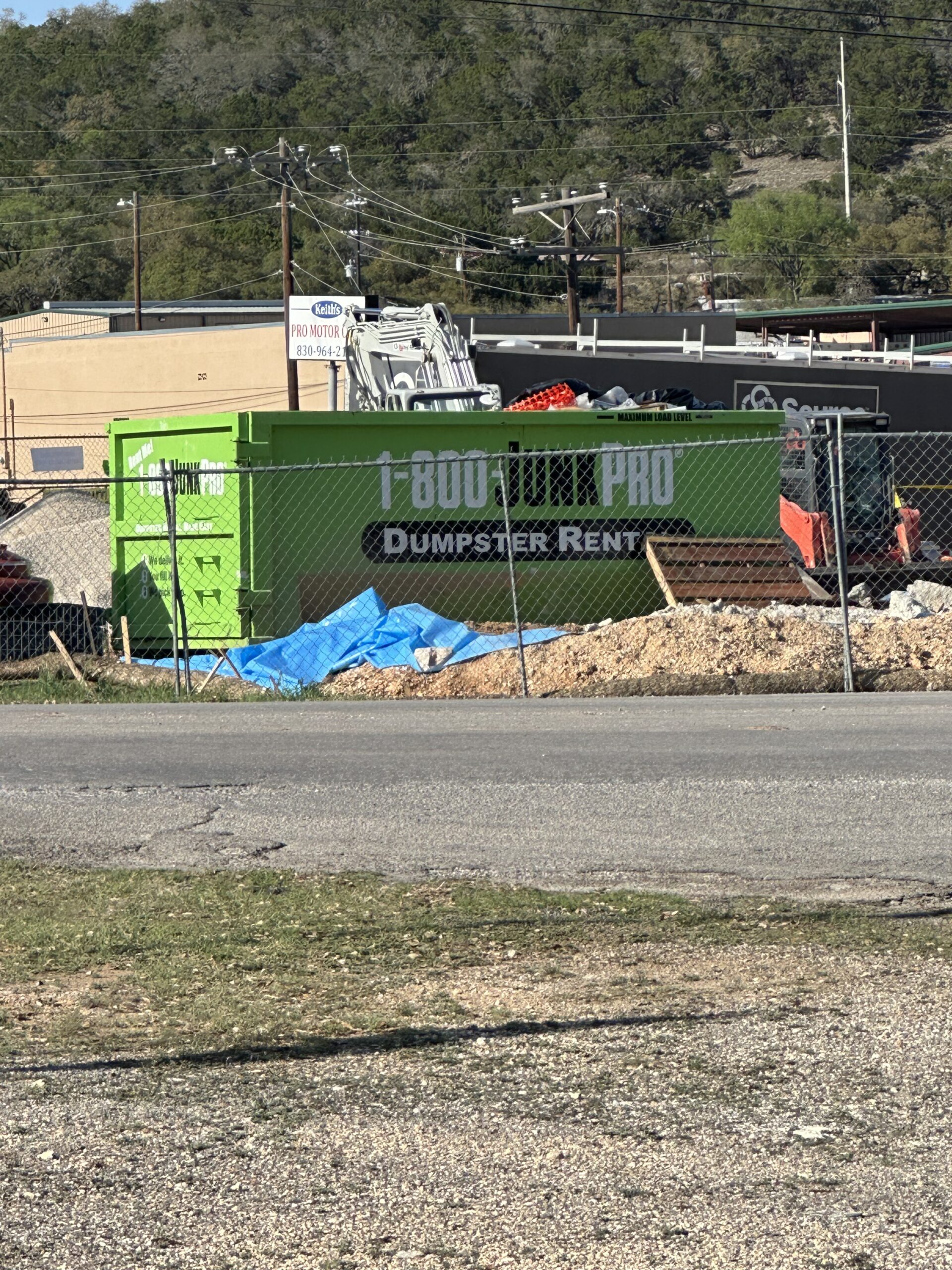 A Large Rented Dumpster in a commercial parking lot surrounded by debris